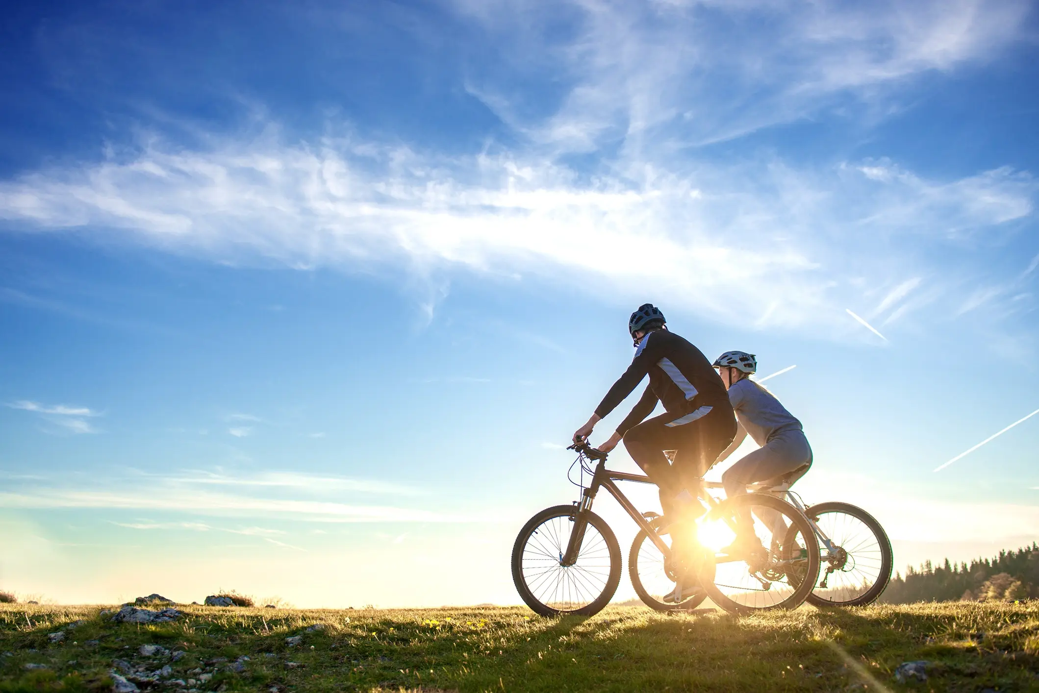 Two cyclists biking through grass