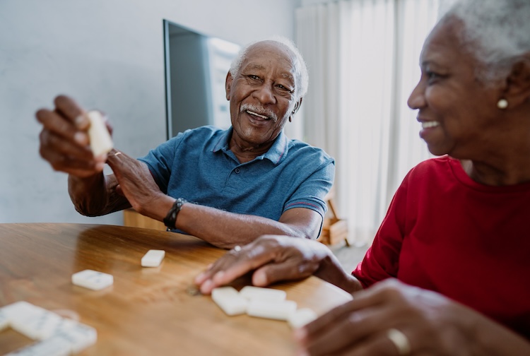 Two elderly people, man and woman, are playing dominoes