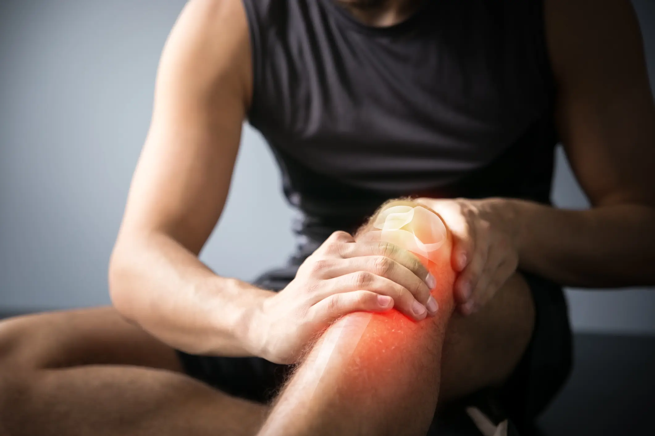 Person touching knee glowing red to indicate pain