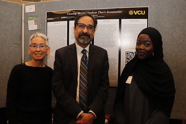 Dr. Rao posing in front of poster with presenters